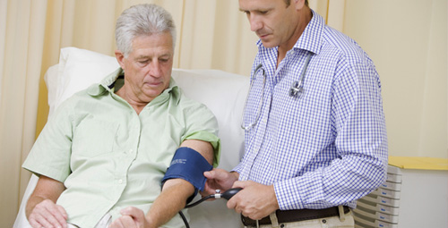 An older man receiving a blood pressure test from a doctor